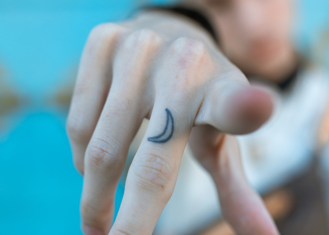 moon finger tattoo on the middle finger